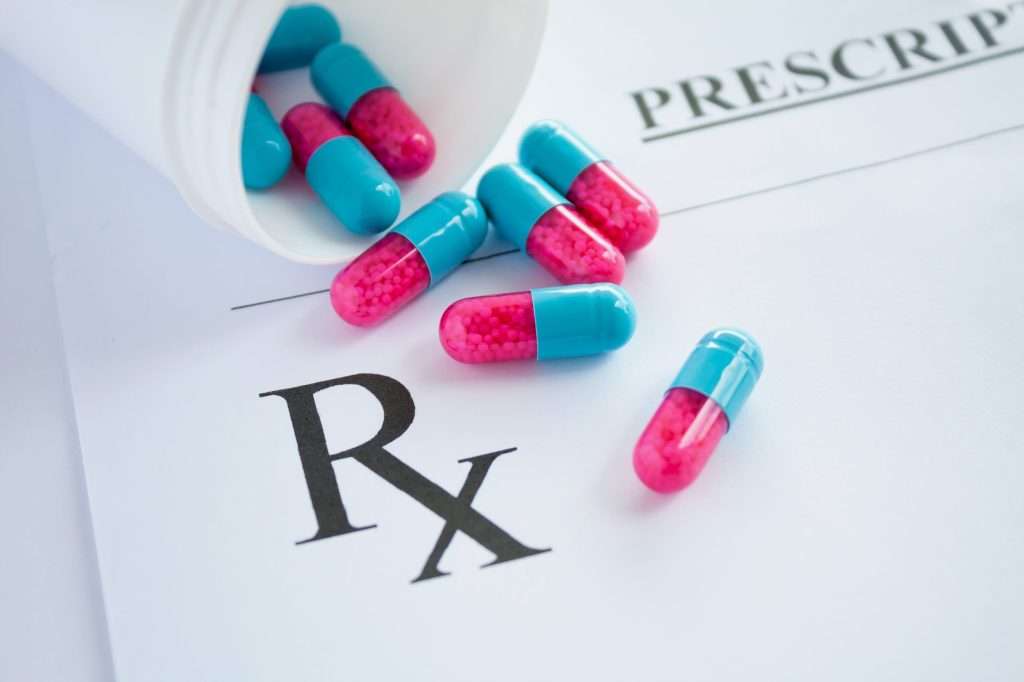 pink and blue pills on a prescription pad
