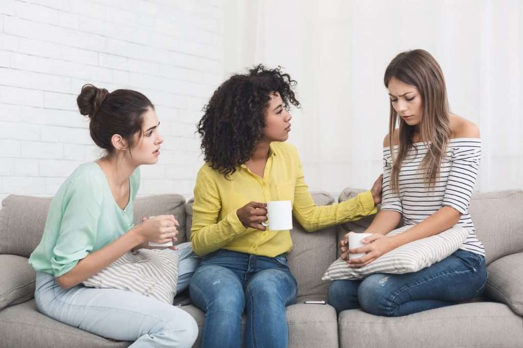 group of women consoling each other on a couch