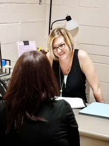 Peer Support Specialist Jessie Taylor talks to a client at her desk in Pratt Kansas